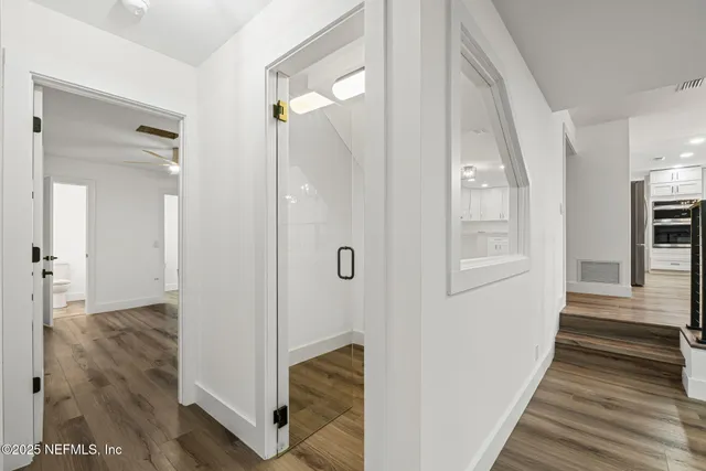 a view of a hallway with wooden floor and staircase