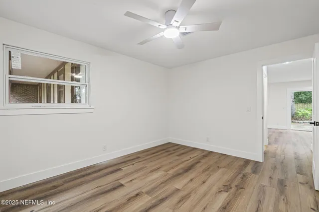 a view of empty room with wooden floor and fan