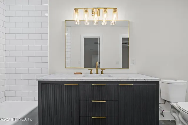 a bathroom with a granite countertop sink a large mirror and a bathtub