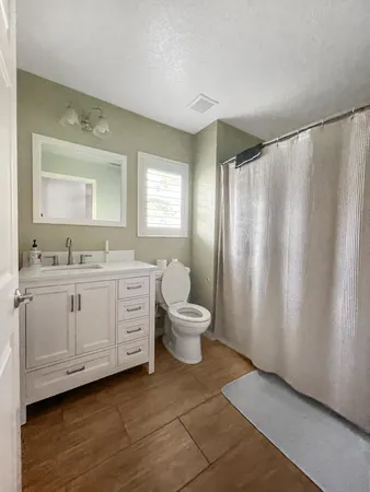 a bathroom with a double vanity sink toilet mirror and window