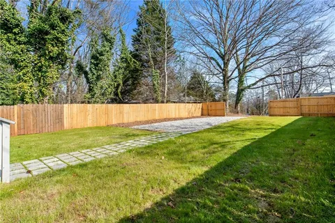 a view of a backyard with a large tree and wooden fence