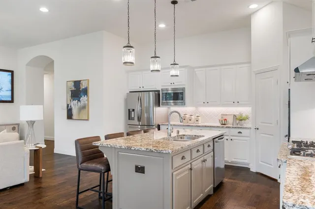 a kitchen with a sink a stove a refrigerator and white cabinets with wooden floor