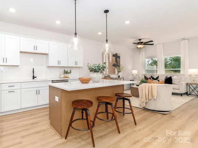 a kitchen with stainless steel appliances kitchen island granite countertop a refrigerator a stove a sink dishwasher and white cabinets with wooden floor
