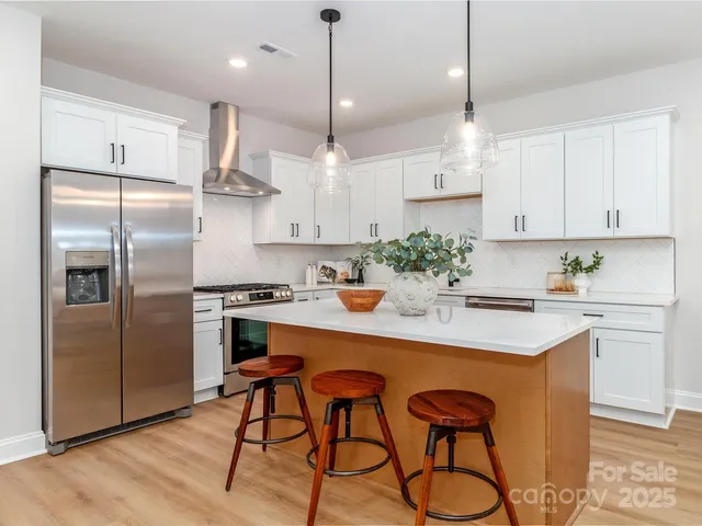 a kitchen with stainless steel appliances a table chairs in it and wooden floors