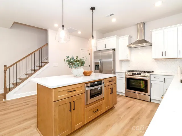a kitchen that has cabinets a sink and a stove with wooden floor