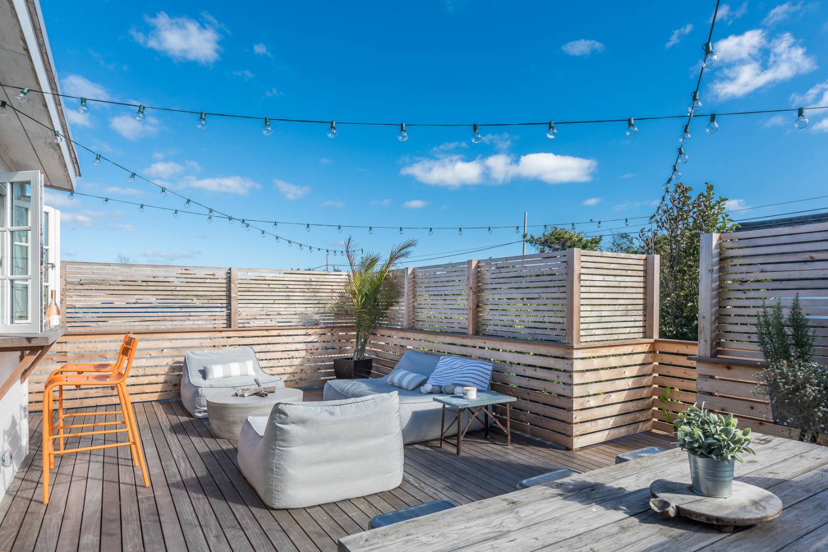 65 Navy Road Montauk, NY 11954 - Photo 12 of 20 a view of a roof deck with dining table and chairs with potted plants