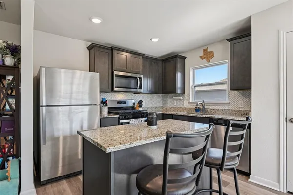 a kitchen with a refrigerator a stove a sink and chairs