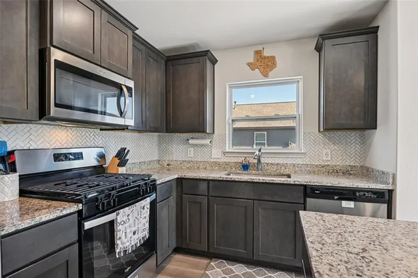 a kitchen with stainless steel appliances granite countertop a stove a sink and a microwave