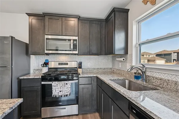 a kitchen with granite countertop a stove a sink and a microwave