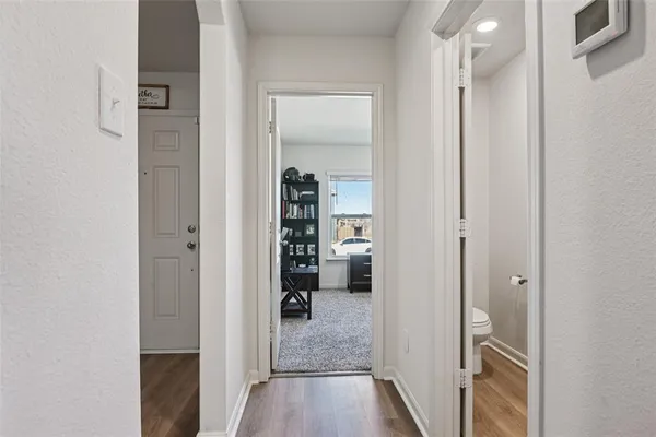 a view of a hallway with wooden floor a living room and space