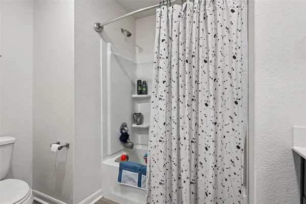 a bathroom with a toilet and a shower curtain