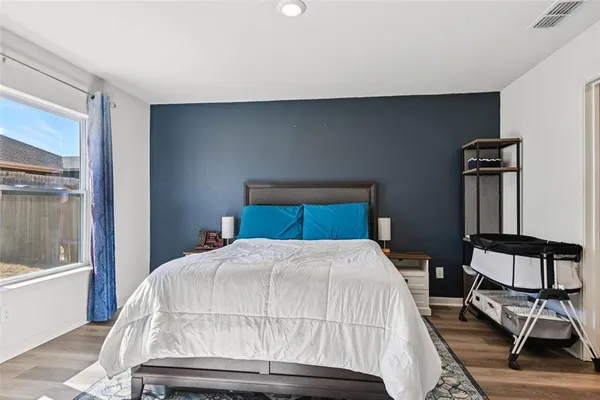 a bedroom with a bed a chair and potted plant on the table