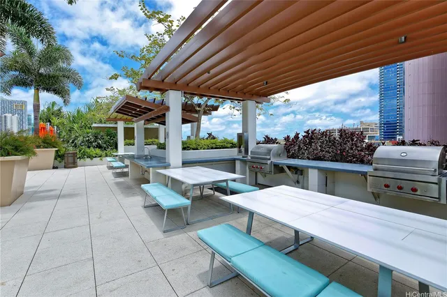 a view of a patio with couches table and chairs with potted plants and a barbeque