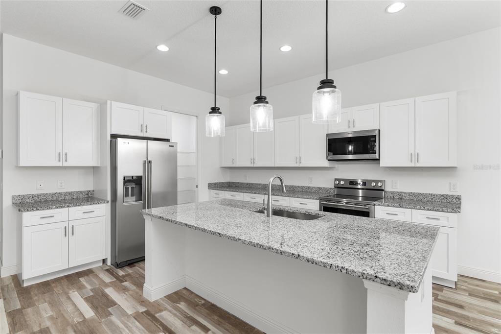 4722 Southeast 25th Loop Ocala, FL 34480 - Photo 15 of 38 a kitchen with stainless steel appliances granite countertop a sink a stove a refrigerator a center island a counter space and cabinets