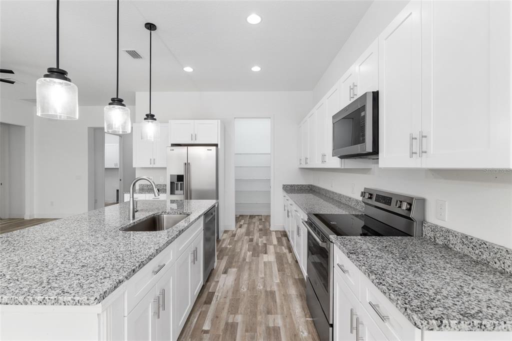 4722 Southeast 25th Loop Ocala, FL 34480 - Photo 16 of 38 a kitchen with stainless steel appliances granite countertop a sink a stove and a wooden floors