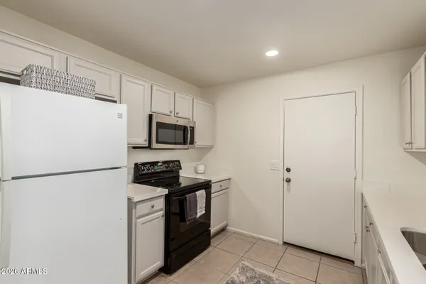 a kitchen with white cabinets and refrigerator