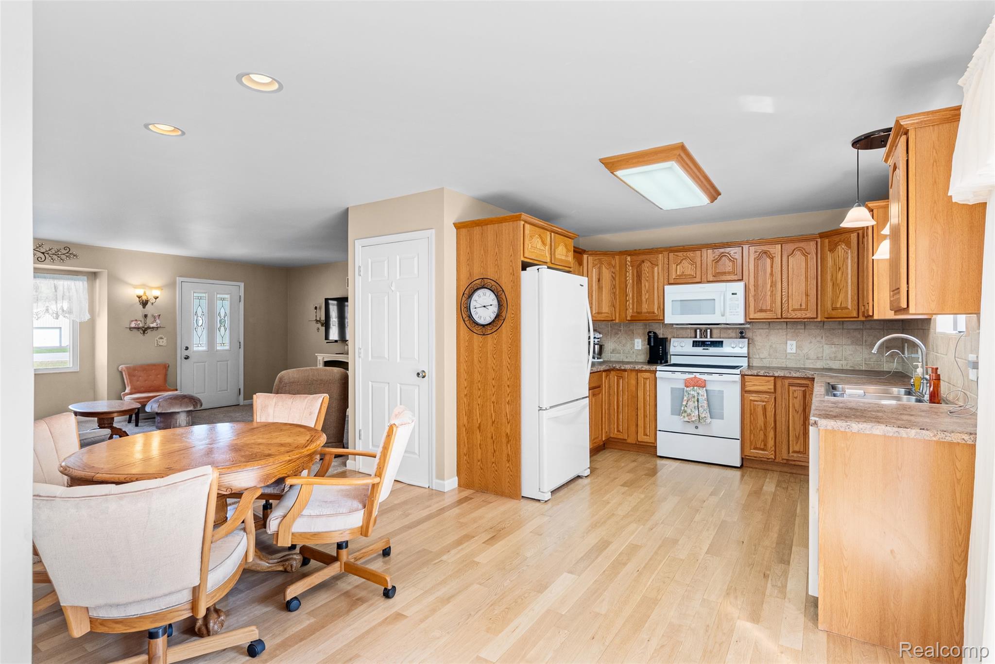 1091 Reid Road Flint, MI 48507 - Photo 14 of 35 Kitchen with light countertops, tasteful backsplash, white appliances, light wood-style floors, and hanging light fixtures