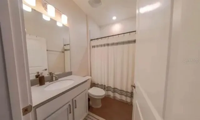 a bathroom with a granite countertop sink toilet a mirror and shower