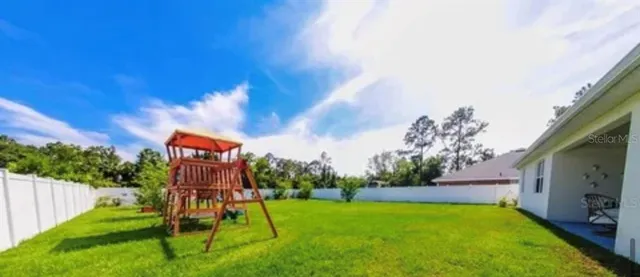 a view of a backyard with plants and a slide