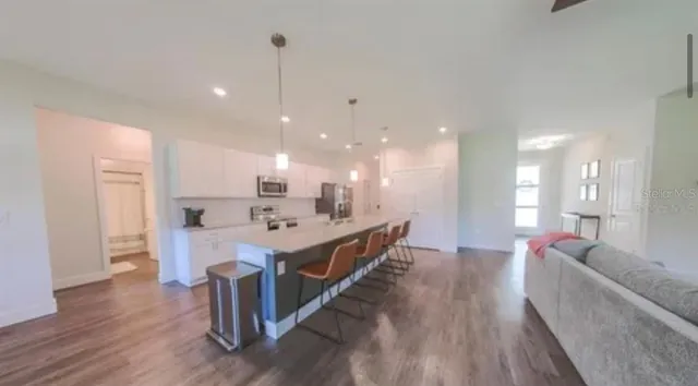 a large white kitchen with a large island oven a sink and chairs