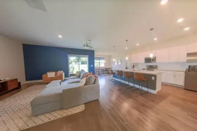 a living room with couches and kitchen view with wooden floor