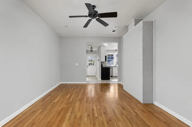 a view of empty room with wooden floor and ceiling fan