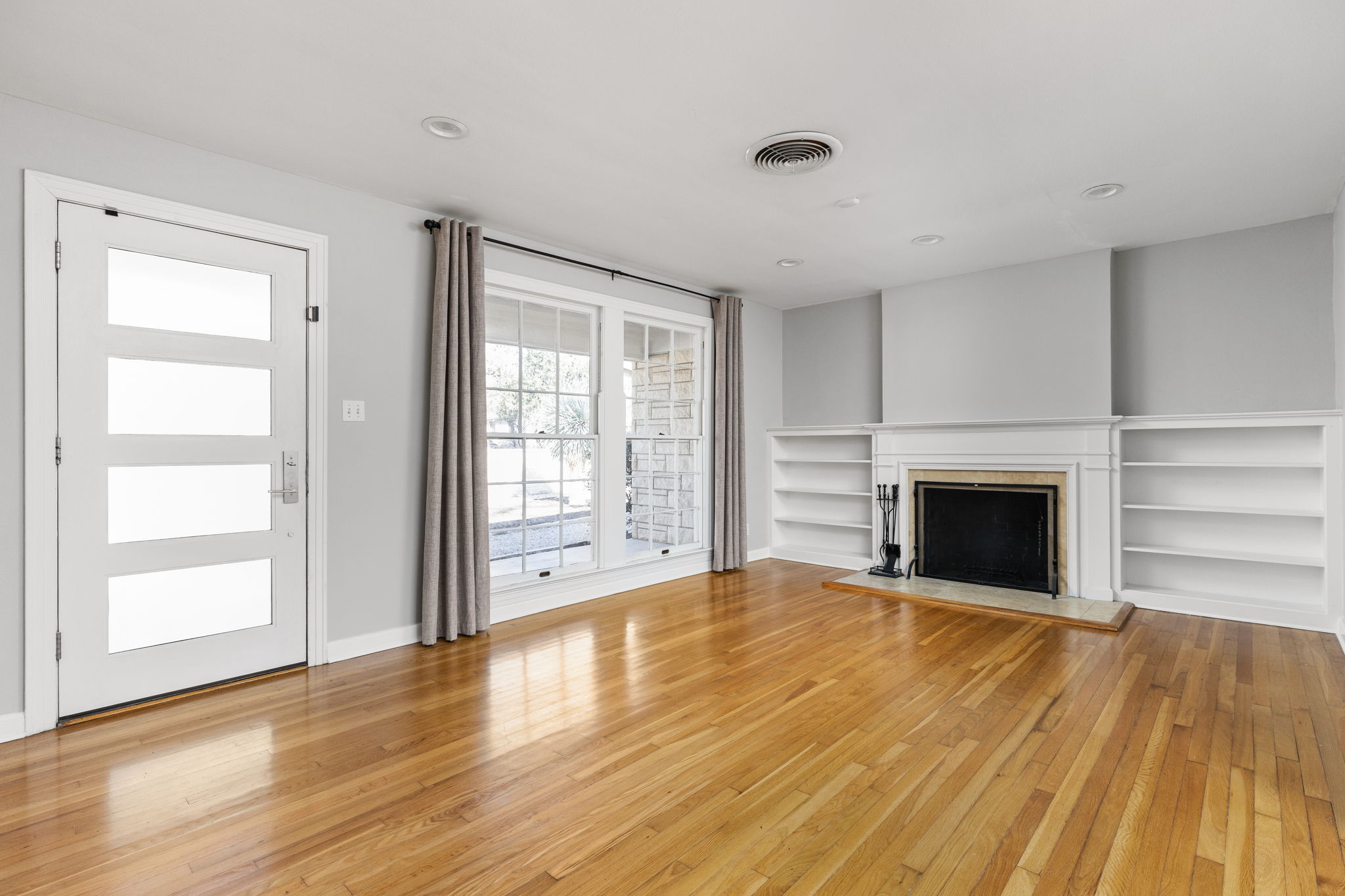 4517 Bull Creek Road Austin, TX 78731 - Photo 5 of 35 a view of empty room with wooden floor and fireplace