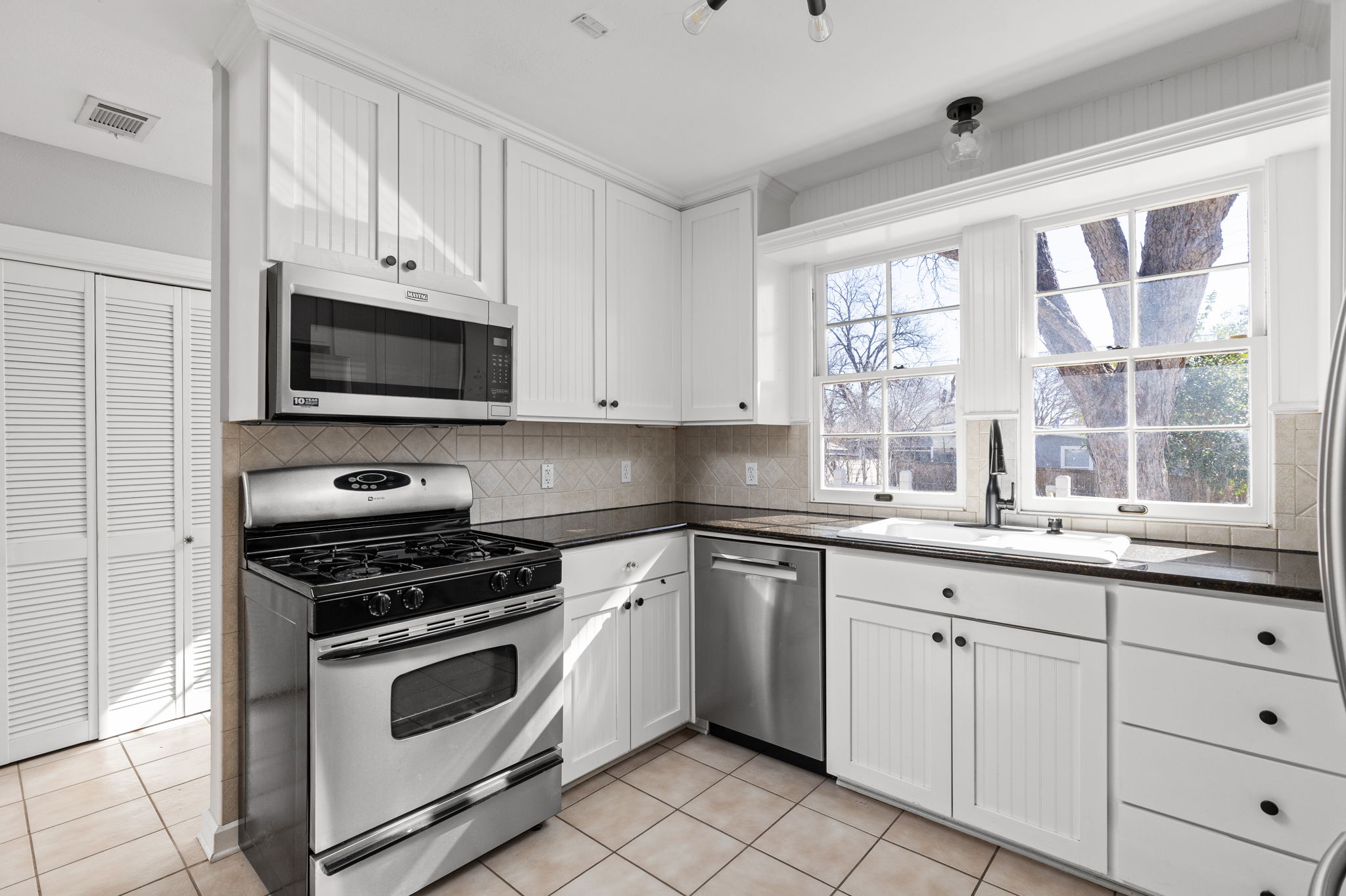 4517 Bull Creek Road Austin, TX 78731 - Photo 9 of 35 a kitchen with granite countertop white cabinets white stainless steel appliances and a sink