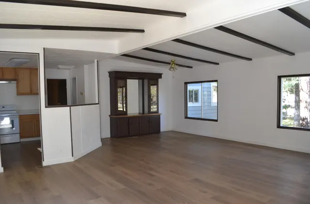 a view of a hallway with wooden floor and a living room