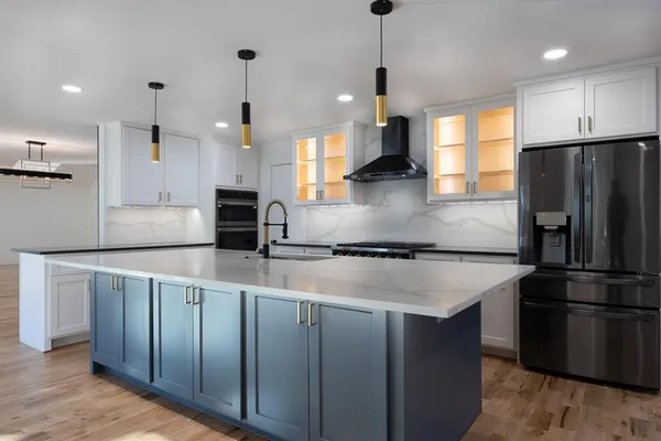 a kitchen with stainless steel appliances granite countertop a sink a refrigerator a stove and a wooden floors