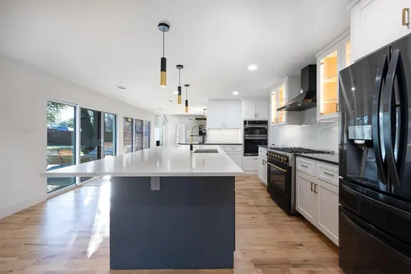 a kitchen with stainless steel appliances granite countertop a sink a stove and a refrigerator
