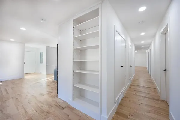 a view of a hallway with wooden floor and a bathroom