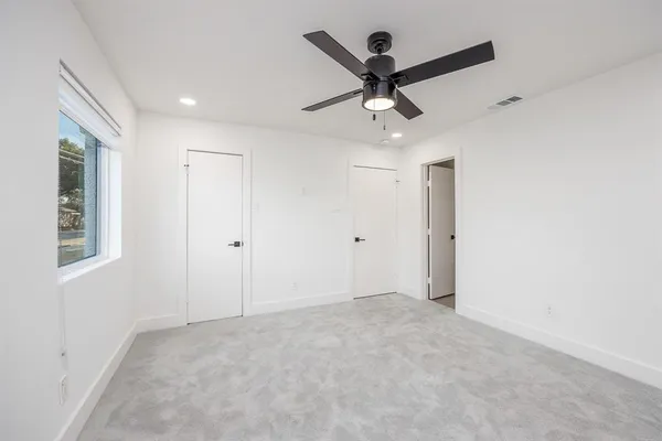 an empty room with a ceiling fan and window