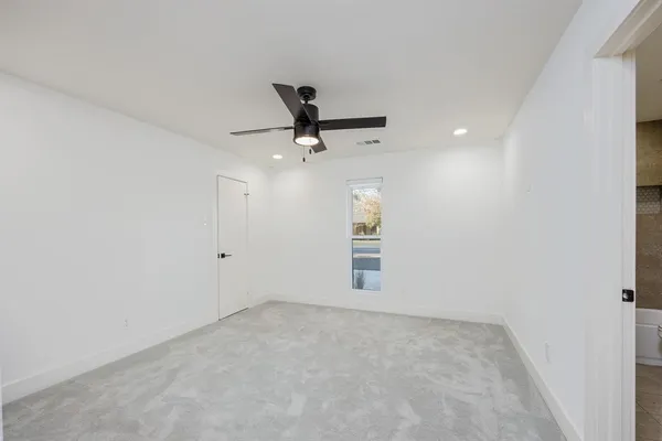 an empty room with a ceiling fan and window