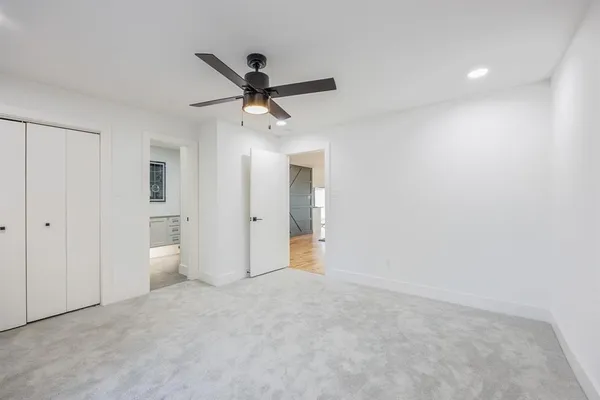 a view of a big room with wooden floor and chandelier fan