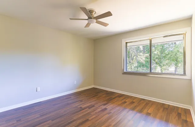 an empty room with wooden floor and windows