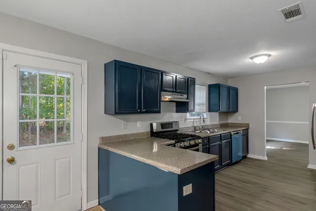 a kitchen with stainless steel appliances granite countertop a sink stove microwave and refrigerator