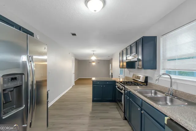 a kitchen with stainless steel appliances granite countertop a sink a stove and a refrigerator