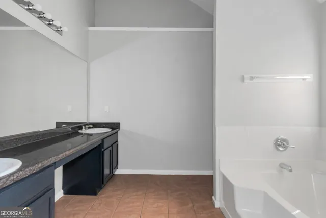 a bathroom with a granite countertop sink and a bathtub