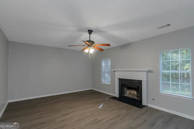 a view of empty room with wooden floor fan and fireplace