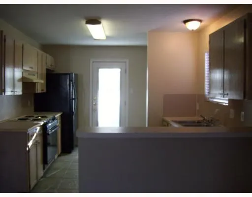 a kitchen that has a lot of cabinets stainless steel appliances and a window