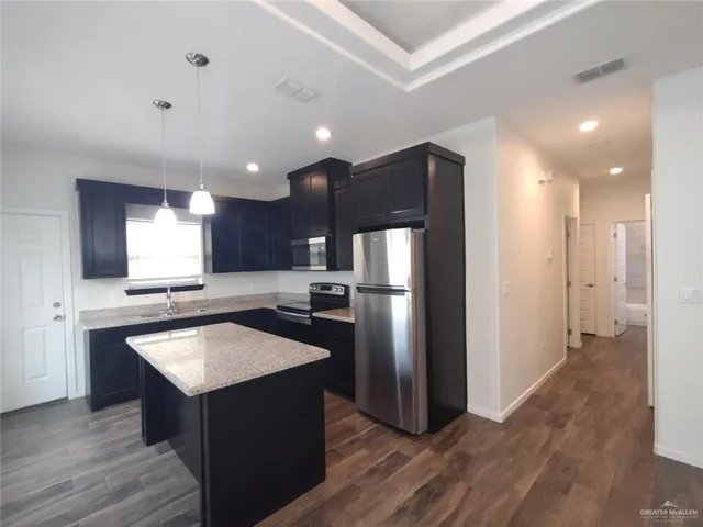 a view of kitchen and empty room with wooden floor