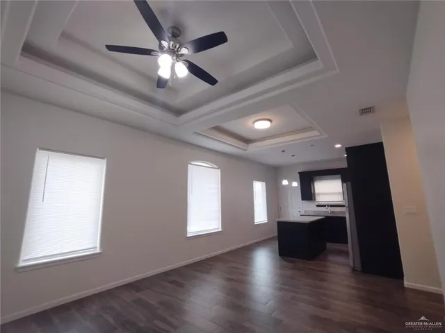 an empty room with wooden floor chandelier fan and windows