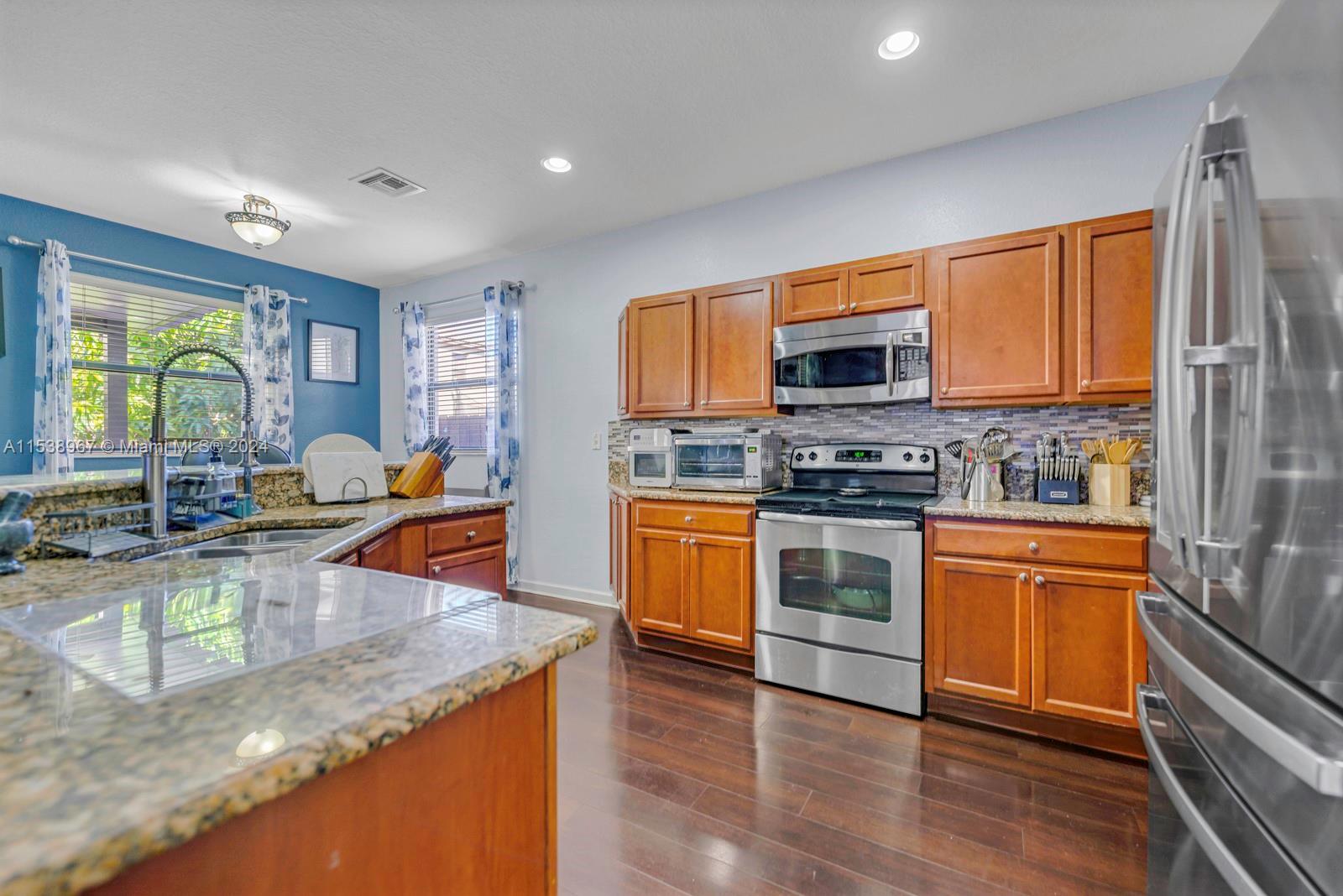 24084 Southwest 113th Path Homestead, FL 33032 - Photo 10 of 37 a kitchen with stainless steel appliances granite countertop a stove a sink and a microwave