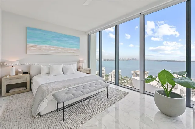 a large white bed in a room next to a window