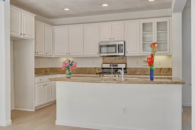 a kitchen with stainless steel appliances granite countertop a sink dishwasher a refrigerator and white cabinets