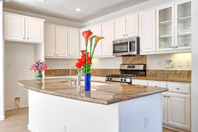 a kitchen with granite countertop a sink stainless steel appliances and cabinets