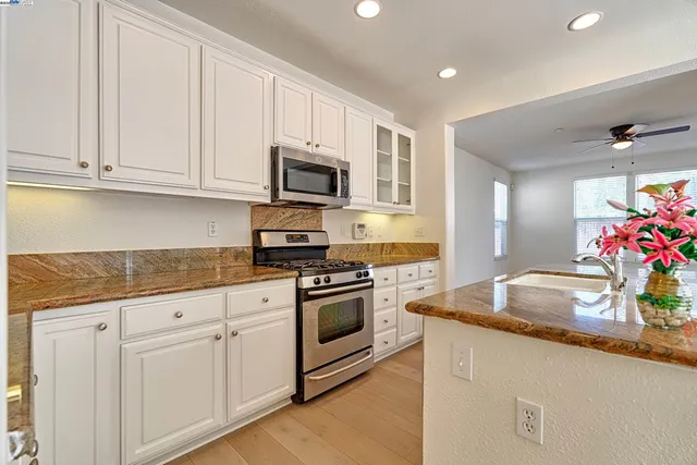 a kitchen with granite countertop white cabinets and stainless steel appliances
