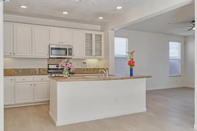 a kitchen with kitchen island granite countertop a stove top oven a sink a counter top space and cabinets