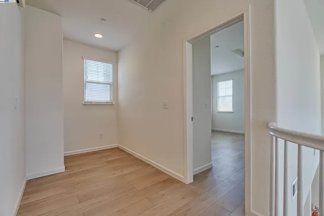 an empty room with wooden floor cabinet and windows